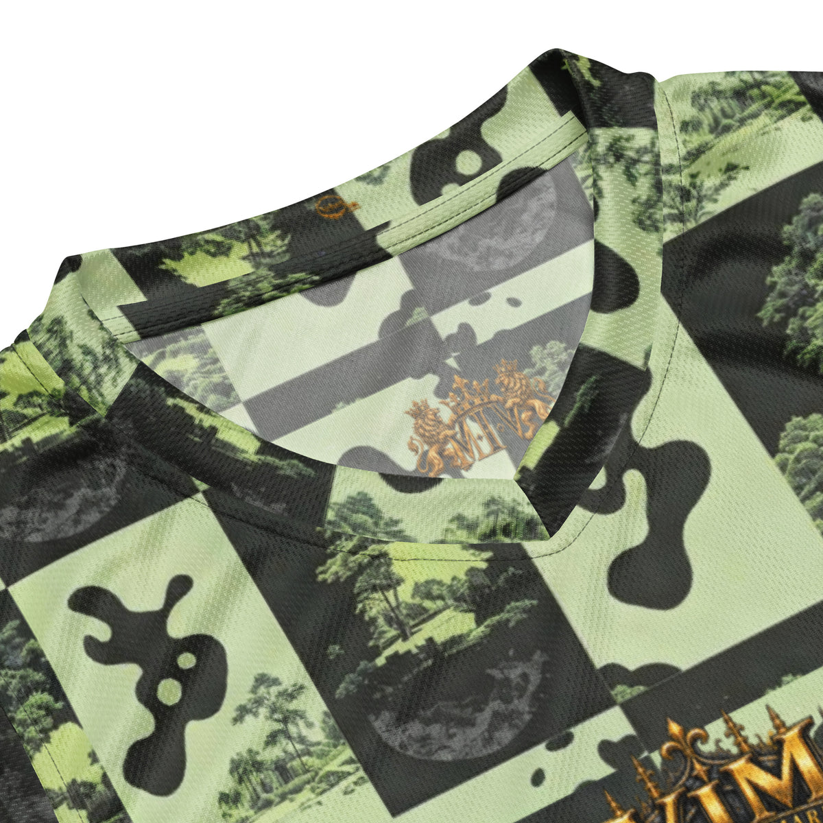 Close-up of a camouflage-patterned athletic jersey with a V-neck collar, featuring black and light green panels with a forest landscape print and gold lettering at the bottom.