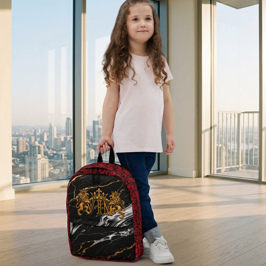 A young girl with long brown hair stands against a light gray studio background, holding a small backpack. The backpack has a black and red patterned design with a gold crest and white wolf graphic.