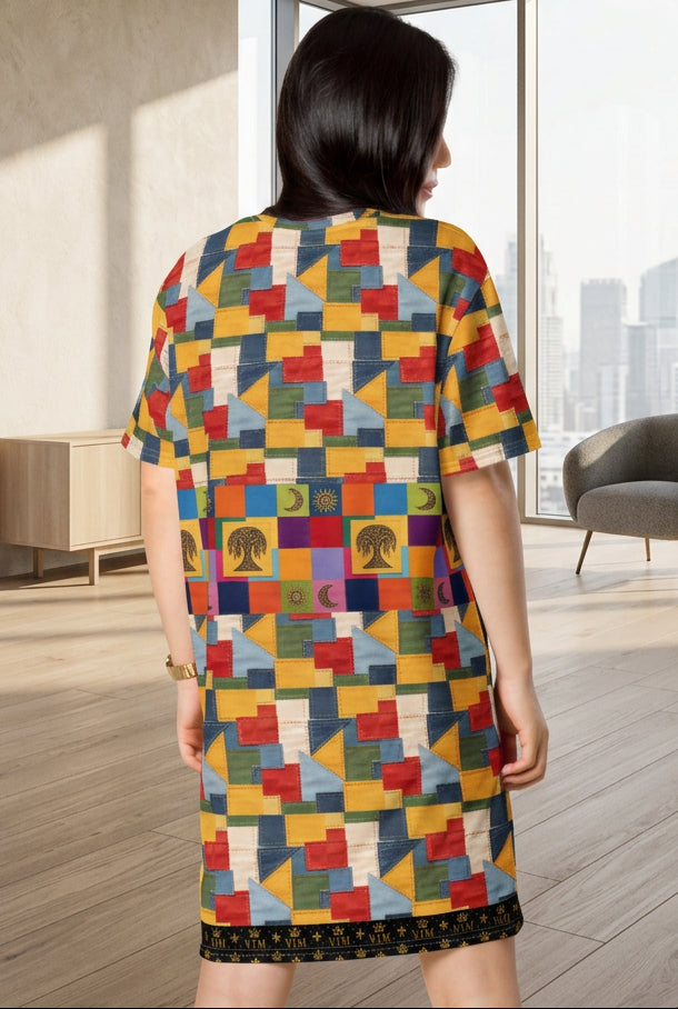 A woman shown from the back wearing a short-sleeve tunic dress with a colorful geometric patchwork print and a black patterned hem, set against a plain white background.
