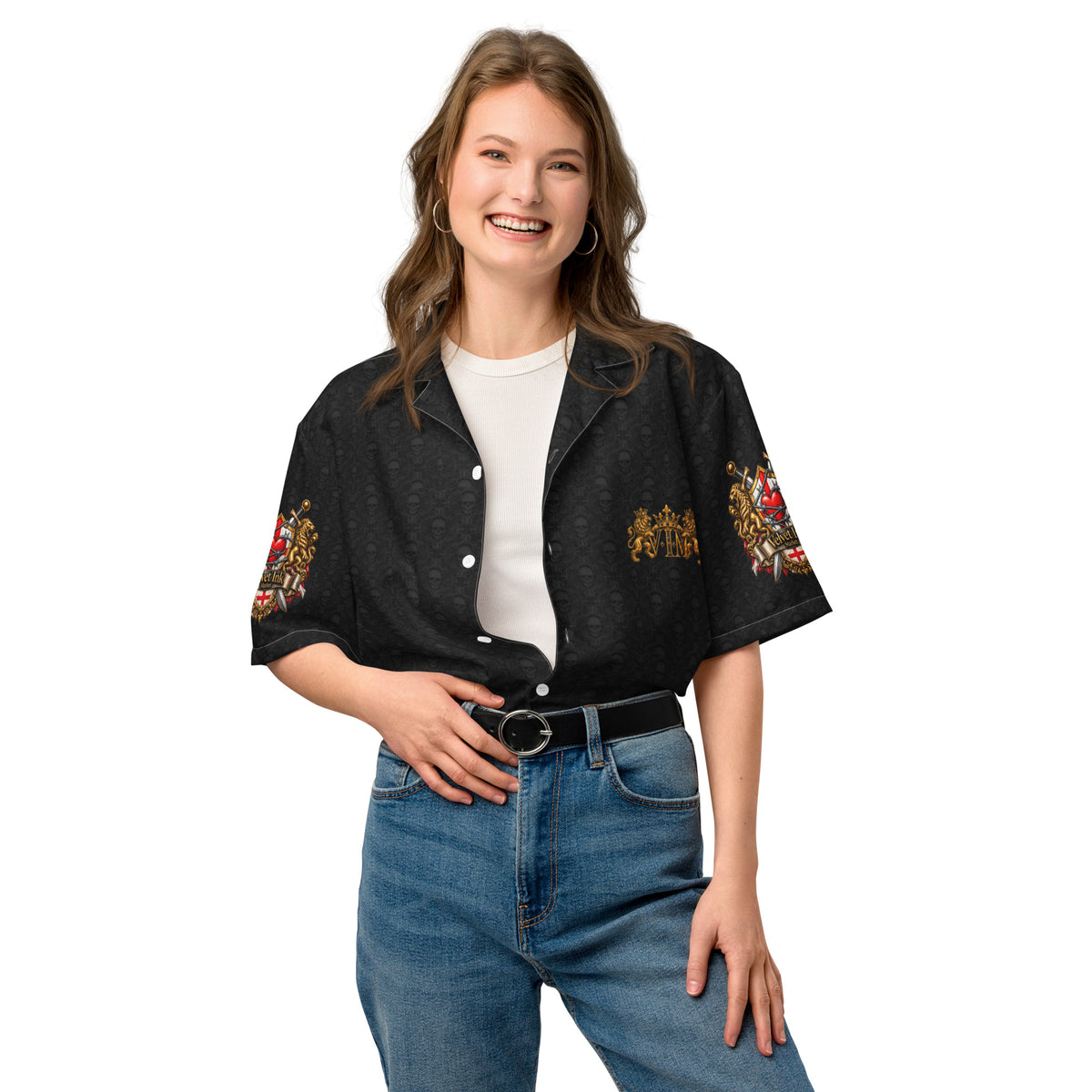 A woman modeling a black short-sleeve button-up shirt with colorful floral embroidery on the sleeves and chest, worn over a white t-shirt and blue jeans against a plain white background.